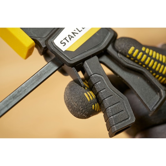 Photo of STANLEY FMHT83270-0 clamp with yellow pad, close-up of black ergonomic handle and trigger.