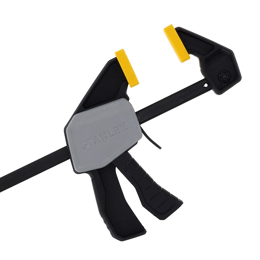 STANLEY FMHT83271-0 trigger clamp with black and gray body, yellow pads, photography, side angle.
