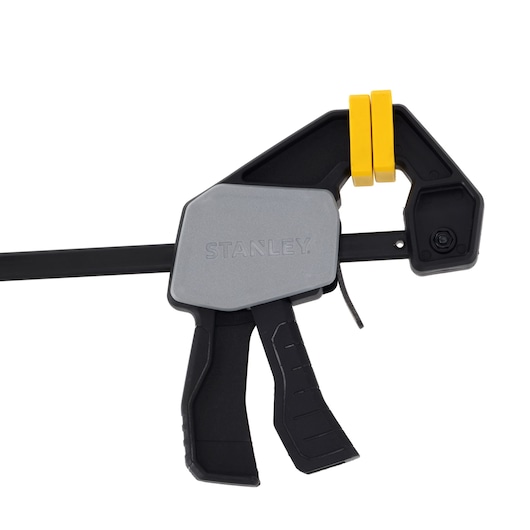 STANLEY FMHT83272-0 trigger clamp with gray body, black handle, and yellow pads, side view, white background.