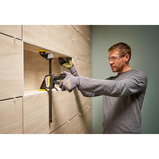 Photo of STANLEY FMHT83274-0 large bar clamp in use holding tiles on wall during installation.