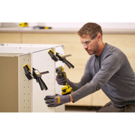 STANLEY FMHT83274-0 clamps securing cabinet panel during assembly, side angle view.