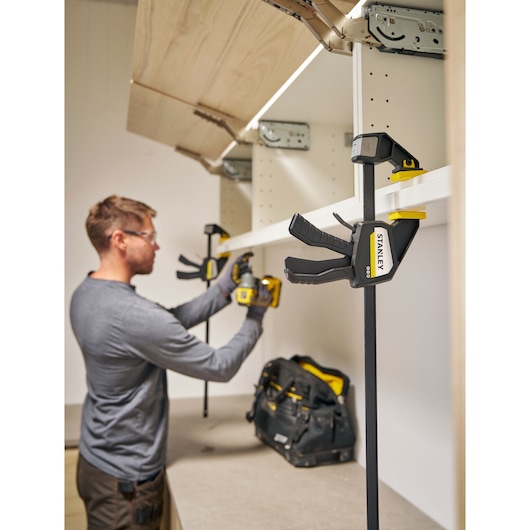 Photo of STANLEY FMHT83276-0 bar clamp holding shelf during cabinet installation.
