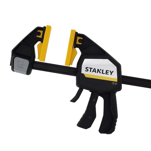 STANLEY FMHT83279-0 trigger clamp with black and yellow jaws, side view on white background.