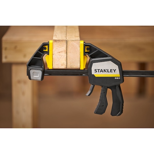 STANLEY FMHT83283-0 clamp securing two wooden boards, close-up photography in workshop setting.