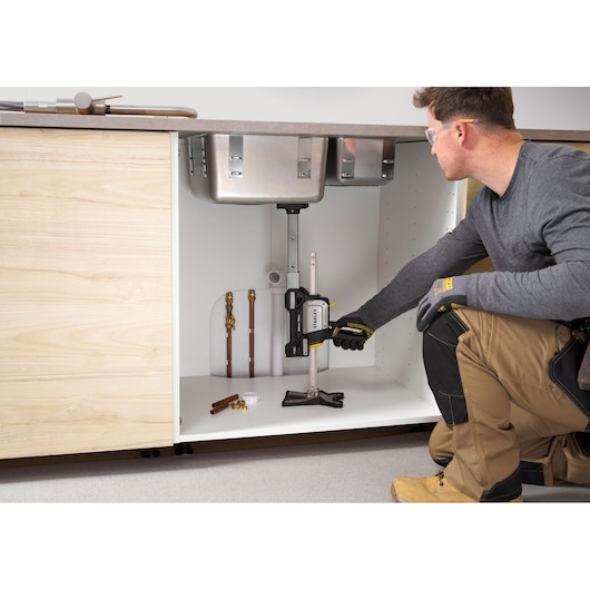 Photo of STANLEY FMHT83554-1 clamping tool securing pipe under kitchen sink, side angle view.