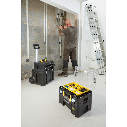 STANLEY FMST1-71970 stackable black toolboxes with yellow handles and organizers, used on a worksite.