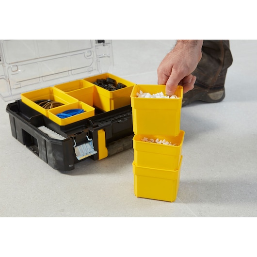 STANLEY FMST1-71970 organizer box with yellow compartments, close-up on hand stacking bins, photo from front angle.