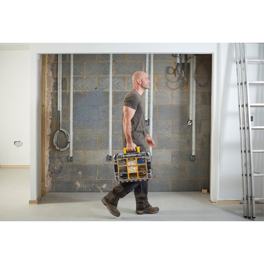 STANLEY FMST1-71970 organizer carried by person in worksite, showing clear compartments and yellow accents.