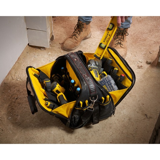 Photo of STANLEY FMST1-73607 tool bag on jobsite floor, open and filled with various hand and power tools.
