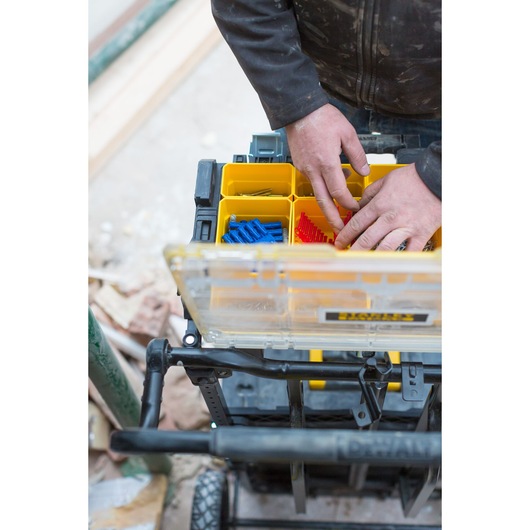 STANLEY FMST1-75678 organizer box with yellow compartments, hands sorting items, top angle photo.
