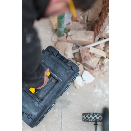 STANLEY FMST1-75682 black tool box with yellow handle being carried on construction site.