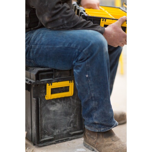 STANLEY FMST1-75682 toolbox with yellow handle, used as a seat, person organizing tool organizer tray.