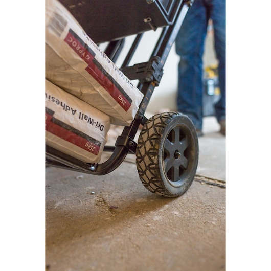 STANLEY FMST1-75683 hand truck wheel close-up carrying construction material indoors.