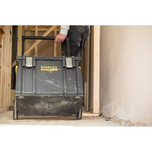 Photo of STANLEY FMST1-75798 rolling tool chest with handle, black, on construction site floor.
