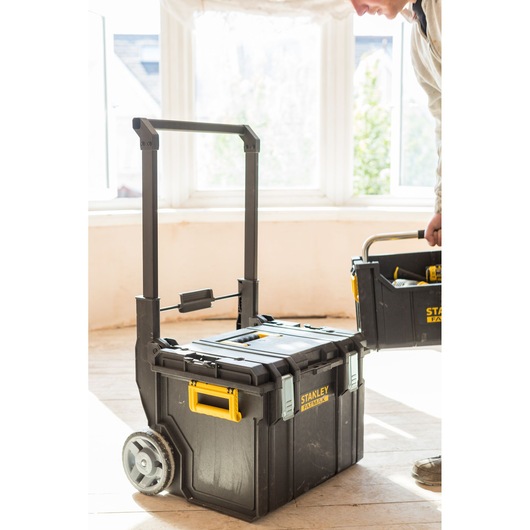 STANLEY FMST1-75798 rolling tool box with yellow handle and wheels, indoor side angle.