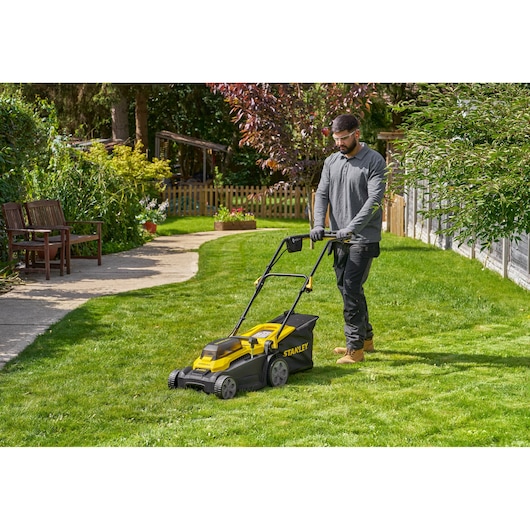 STANLEY SCMWP3701N lawn mower in use on green lawn with person pushing, outdoor garden setting.