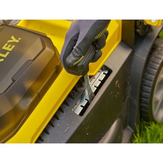STANLEY SCMWP3701N lawn mower height adjustment being set with gloved hand, close-up photography.