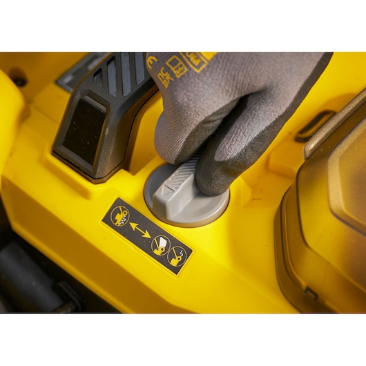 STANLEY SCMWP3701N lawn mower control knob close-up, yellow body, glove hand, top angle.