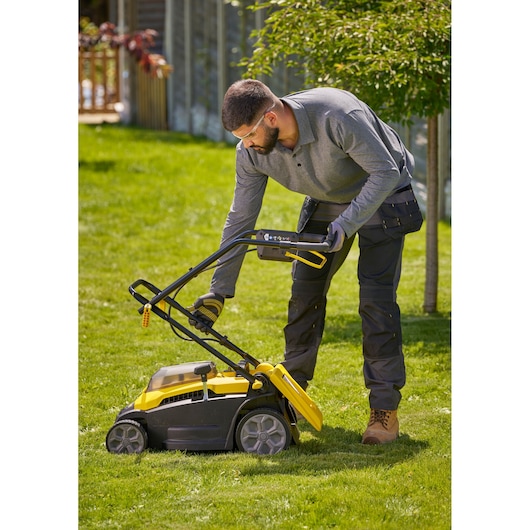 Stanley SCMWP3701N lawn mower with yellow and black body in use on green grass outdoors.