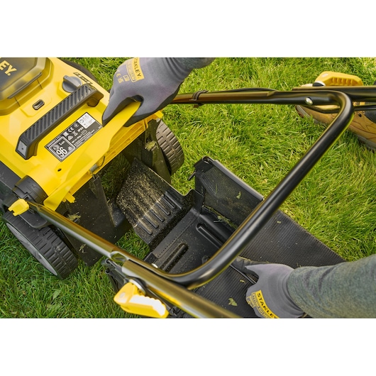STANLEY SCMWP3701N lawn mower, top view, showing yellow body, handle, and grass catcher on lawn.