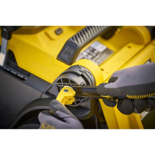 STANLEY SCMWP3701N lawn mower adjustment lever close-up, yellow and black components, gloved hand.