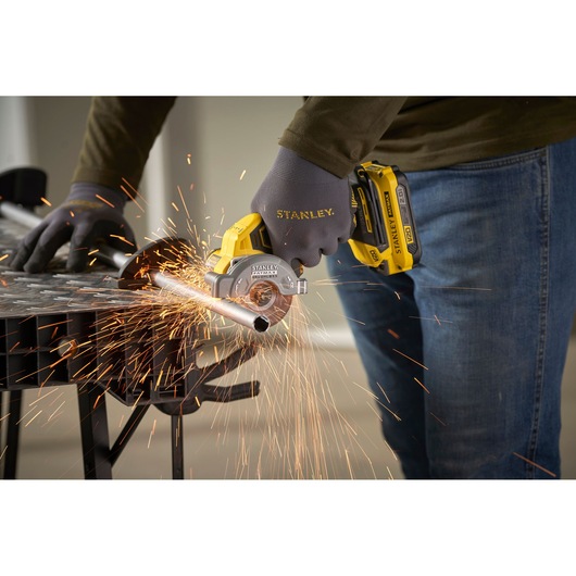 STANLEY SFMCM300B compact cordless metal cutter in use, cutting metal pipe, close-up with sparks.