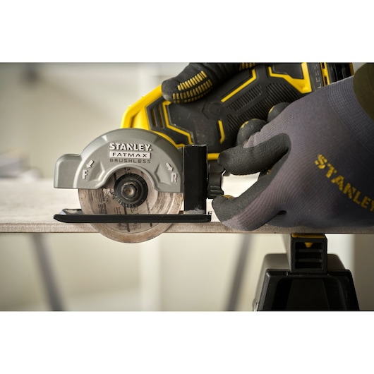 STANLEY SFMCM300B compact circular saw side view, cutting wood, held by gloved hand.