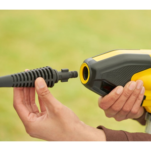 STANLEY SFMCPC93M1 pressure washer nozzle connection close-up, yellow and black tool held by hand.