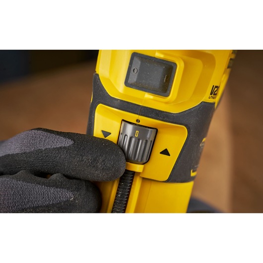 STANLEY SFMCW400B detail view of speed control switch on yellow power tool held by gloved hand.