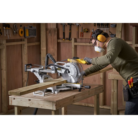 STANLEY SM1800 sliding mitre saw on workbench, used to cut wood in a workshop setting.