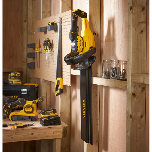 STANLEY STCHT8255M1 photography of yellow and black pole saw hanging in workshop, tools visible nearby.