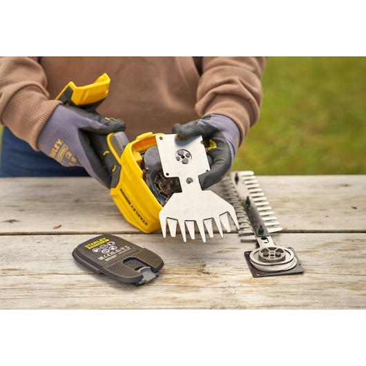 STANLEY STCSS20D1 cordless shear kit being assembled on wooden table outdoors, gloves visible.