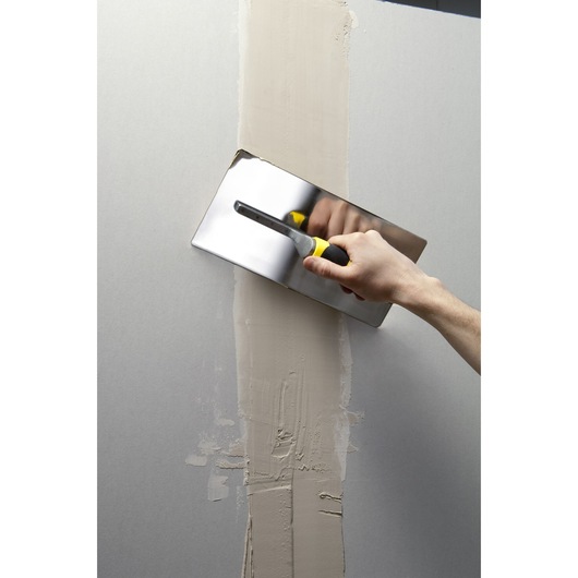 STANLEY STHT0-05900 plastering trowel smoothing wall joint, frontal angle, yellow and black handle.