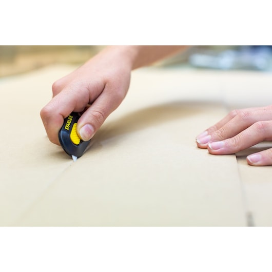 STANLEY STHT0-10292 utility knife cutting cardboard, product photography close-up.