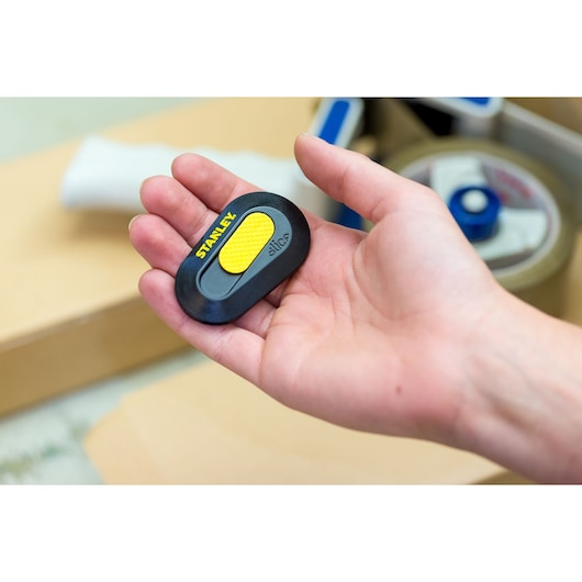STANLEY STHT0-10292 compact safety cutter with yellow grip, shown in hand, close-up.
