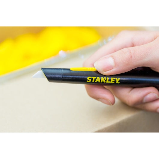 Photo of STANLEY STHT0-10293 utility knife with black handle and yellow slider, held in hand.