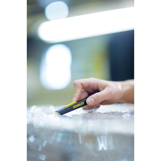 Photo of STANLEY STHT0-10293 utility knife held in hand cutting packaging wrap.