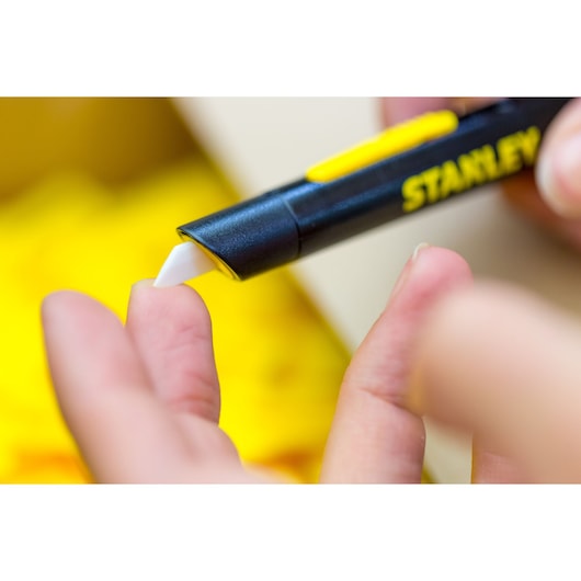 Photo of STANLEY STHT0-10293 safety knife with white blade used on a hand, close-up, product photography.