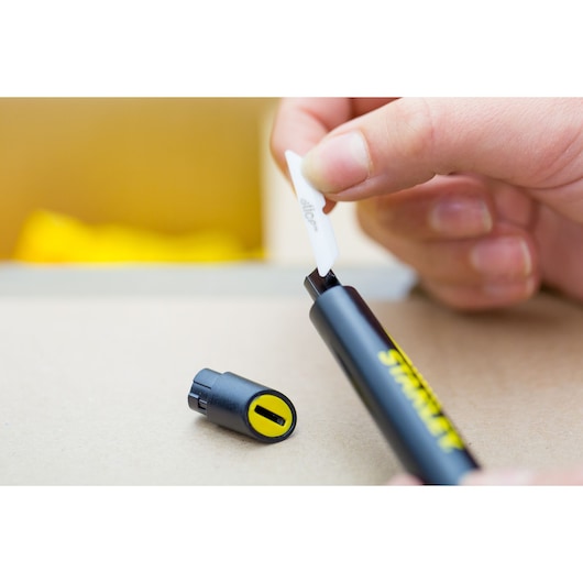 STANLEY STHT0-10293 utility knife, black and yellow handle, blade being inserted, close-up.