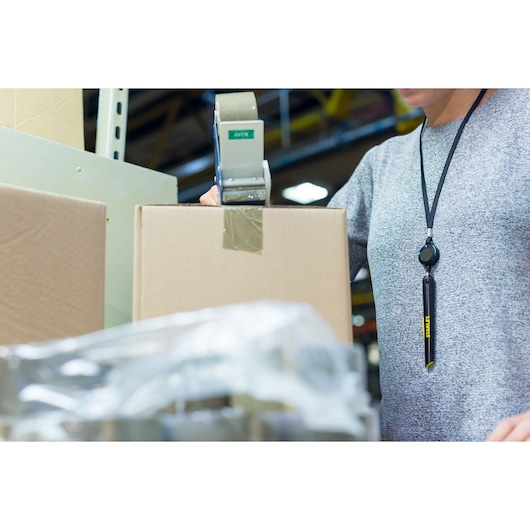 STANLEY STHT0-10293 utility knife hanging on lanyard worn by person packing cardboard box.
