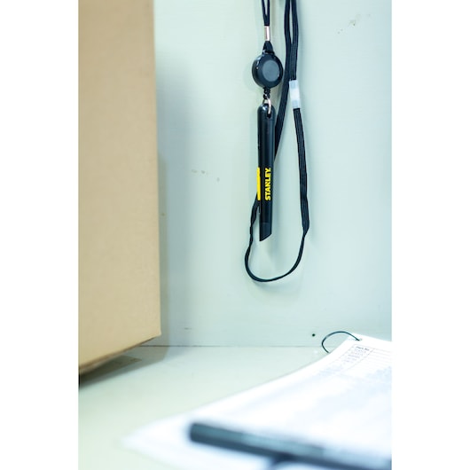 STANLEY STHT0-10293 black utility knife with lanyard, hanging vertically, close-up indoor photo.