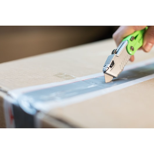 Photo of STANLEY STHT0-10823 utility knife cutting tape on a cardboard box, close-up angle.
