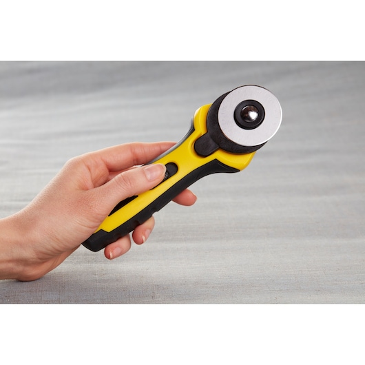 Hand holding STANLEY STHT0-11942 rotary cutter, yellow and black handle, side view, photography.