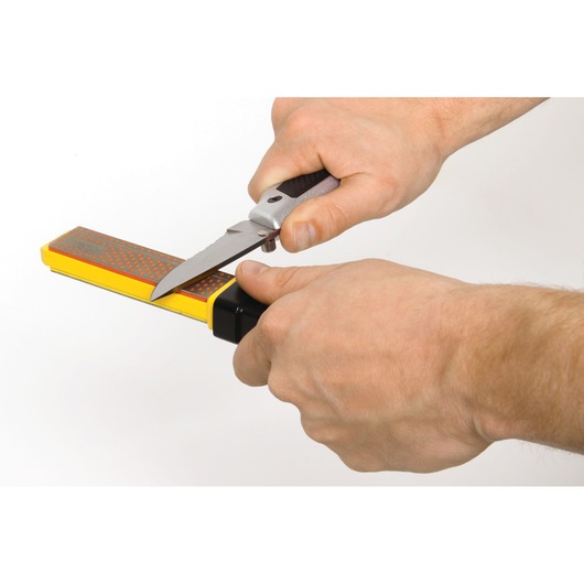 STANLEY STHT0-16144 knife sharpener in use, sharpening a folding knife, close-up, white background.