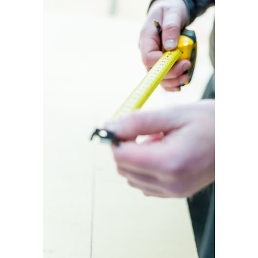 STANLEY STHT0-36118 tape measure held by hands, photography, yellow tape extended.