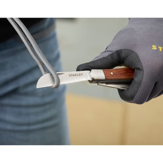 STANLEY STHT0-62687 pocket knife with wood handle cutting cable, close-up photography.