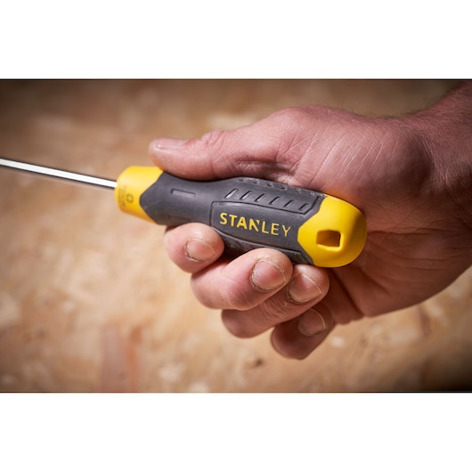 STANLEY STHT0-65153 screwdriver with yellow and black handle held in a hand, close-up side view.