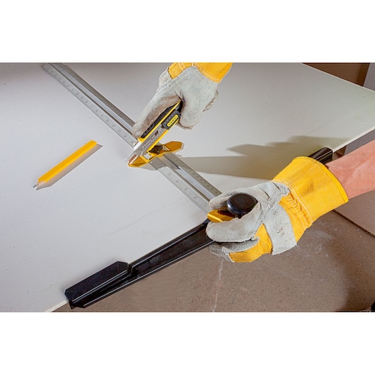 STANLEY STHT1-05933 photography of utility knife cutting drywall with gloves and measuring tool.