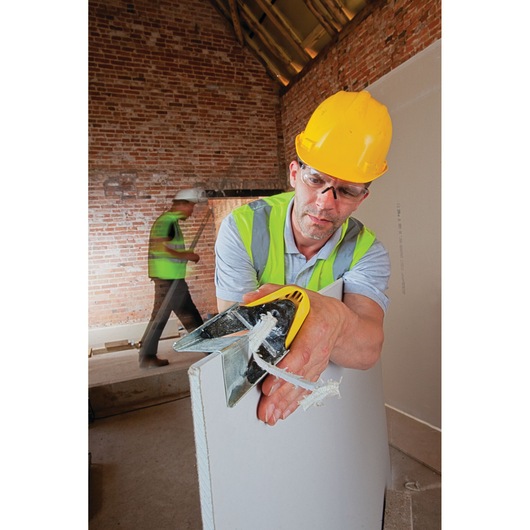 STANLEY STHT1-05937 hand tool for cutting drywall, shown in use on construction site.