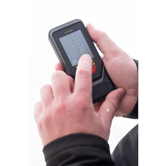 STANLEY STHT1-77142 laser distance measurer held in hand, touchscreen interface visible, close-up photo.